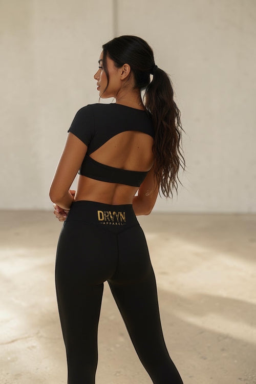 Drvyn Apparel black high-rise nylon-spandex leggings with a sculpted fit and gold logo detail.
